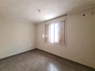Foto de um cômodo vazio com paredes brancas e piso de concreto.