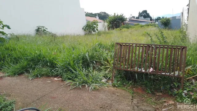 Foto da fachada de uma propriedade com vegetação alta e grama no jardim.