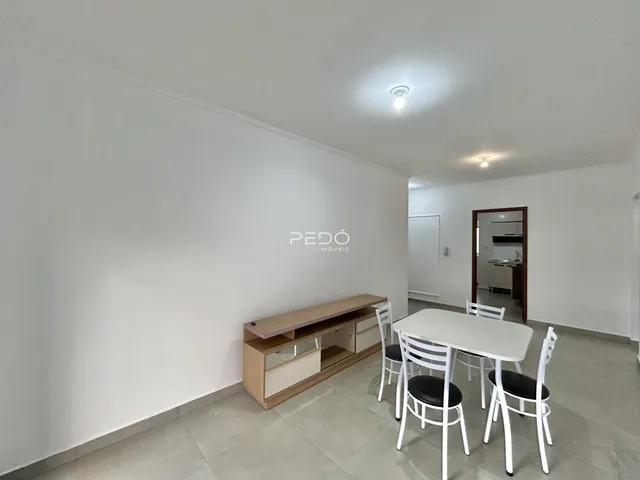 Ambiente interno de sala com mesa de jantar e estante de madeira.