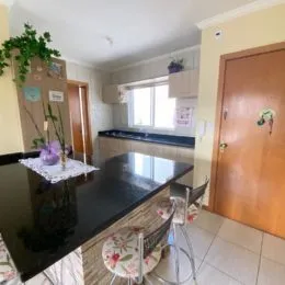 Foto de uma área de cozinha com bancada escura e piso de madeira.