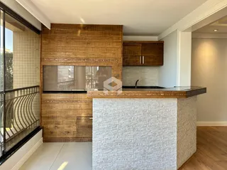 Interior de uma sala de estar com painel de madeira e ilha de cozinha.
