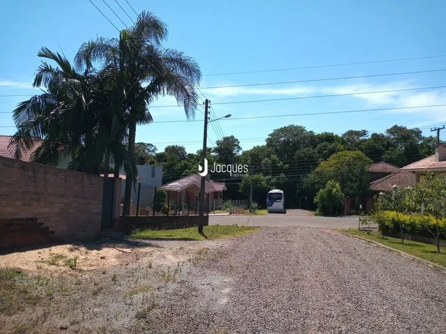 Vista externa de uma propriedade com muro de tijolos e vegetação ao fundo.