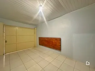 Interior de uma sala com piso de cerâmica e parede de madeira.