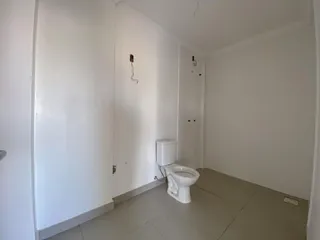 Foto interna de um banheiro com piso claro e vaso sanitário branco.