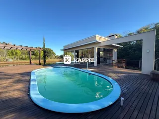Foto de uma piscina externa em um pátio de madeira adjacente a uma residência moderna.