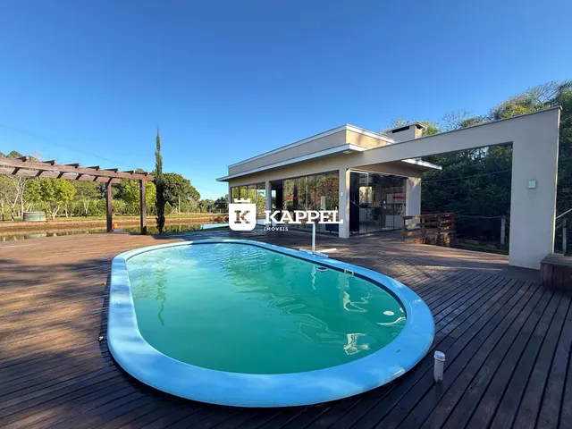 Foto de uma piscina externa em um pátio de madeira adjacente a uma residência moderna.