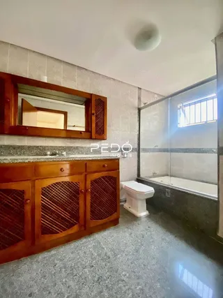 Interior de um banheiro com armários de madeira e banheira.