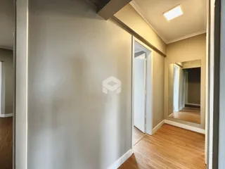 Corredor interno de uma residência com piso de madeira clara.