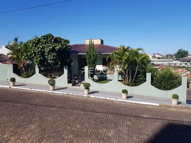 Vista da fachada de uma residência com muro e vegetação em Lajeado.