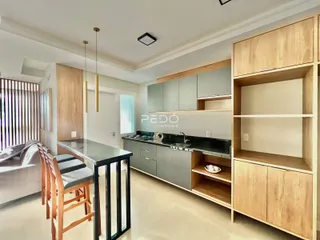 Sala de estar e cozinha de um imóvel em Lajeado com armários de madeira.