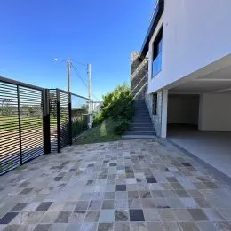 Área externa pavimentada com lajotas de pedra na fachada da propriedade.
