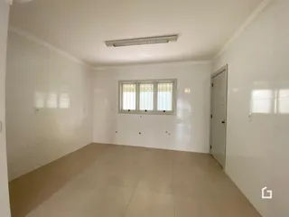 Vista interna de um ambiente com paredes brancas e piso claro.