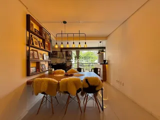 Uma mesa de jantar de madeira longa é visível no ambiente.
