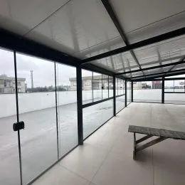Vista de um espaço interno com estrutura de vidro e metal.