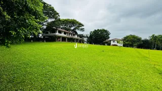 Vista da propriedade com gramado verde e árvores ao fundo.