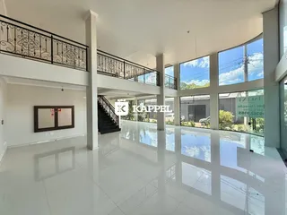 Vista ampla de um hall com piso claro e janelas amplas em um imóvel.