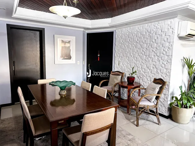 Uma sala de jantar com mesa de madeira e cadeiras em um imóvel no Brasil.