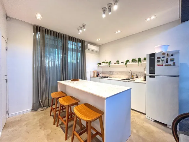 Vista de uma cozinha moderna com bancada de mármore e estantes decorativas.