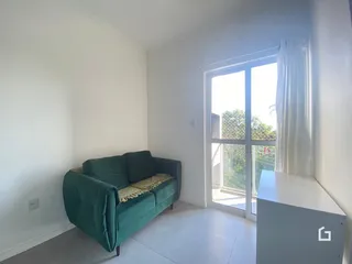 Sala de estar com sofá verde e grande janela de vidro.