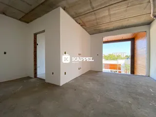 Ambiente interno vazio com paredes brancas e piso de concreto exposto.