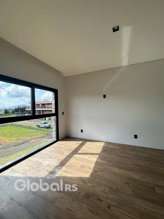 Uma vista da sala de um imóvel em Lajeado, com piso de madeira e grande janela.