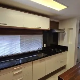 Foto de uma cozinha com armários brancos e bancadas escuras.