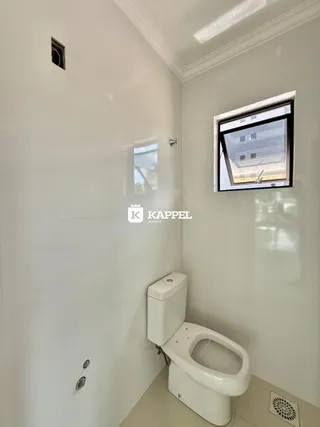 Foto de um banheiro interno com parede branca e uma janela.