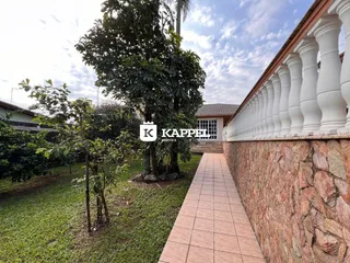 Vista externa da propriedade mostrando um jardim e uma parede de pedra com balaustrada branca.