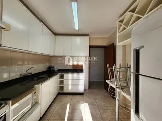Uma cozinha com armários brancos e bancadas escuras.