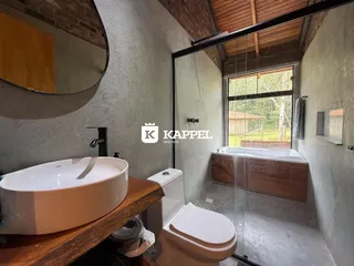 Banheiro com bancada de madeira e box de vidro transparente.
