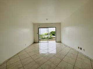 Espaço interno amplo com piso de cerâmica e porta de vidro para o exterior.