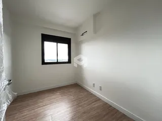 Ambiente interno de um cômodo com piso de madeira e janela.