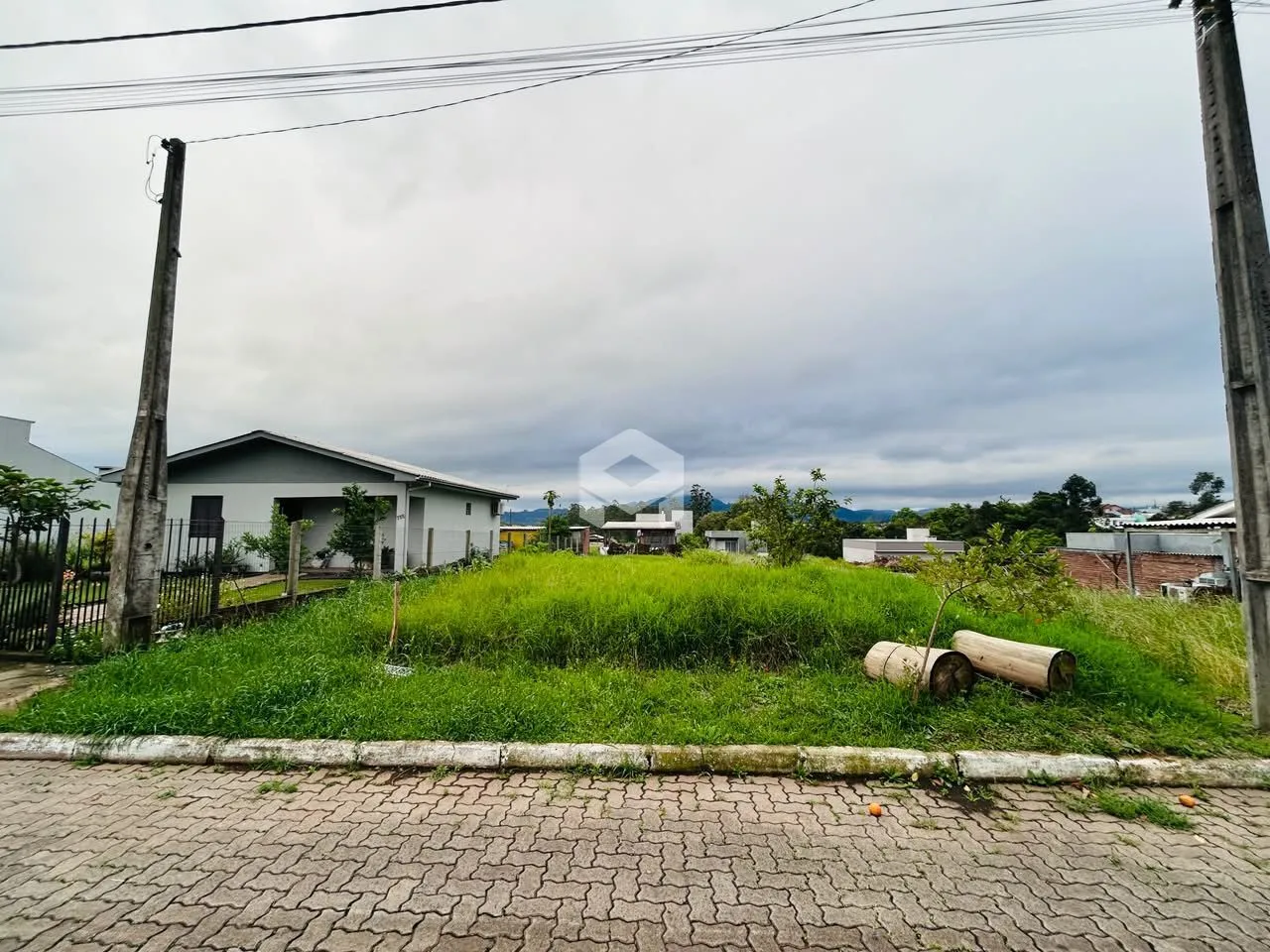 Vista da propriedade com gramado e cerca ao lado de uma estrada.