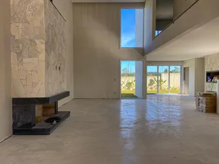 Ambiente amplo com piso claro e parede de pedra aparente em uma residência.
