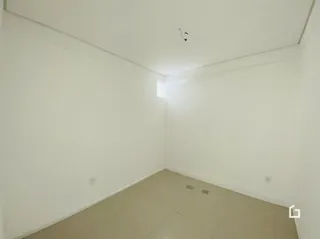 Vista interna de um cômodo vazio com paredes brancas.