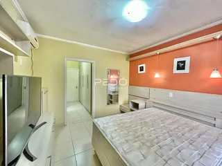 Quarto com cabeceira e armário em um ambiente com parede de destaque laranja.