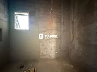 Foto de um cômodo interno com paredes de concreto aparente e uma janela.