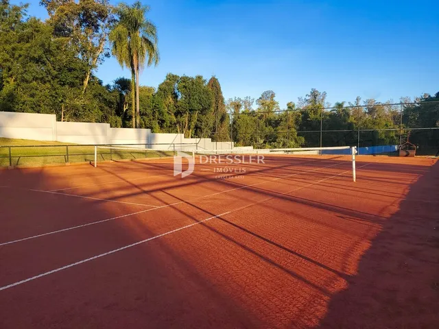 Uma vista de uma quadra esportiva externa com grama e árvores ao fundo.