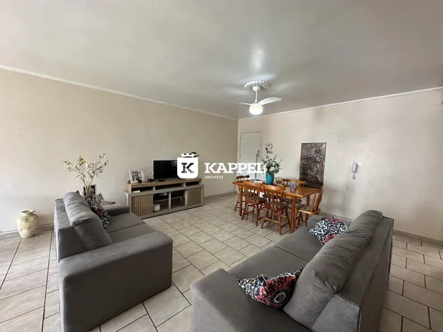 Sala de estar com sofá grande e mesa de jantar em um ambiente claro.