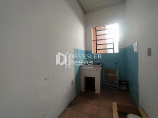 Vista interna de um corredor com paredes brancas e piso de terracota.