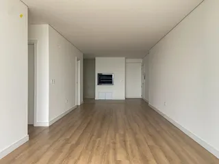 Foto de um corredor interno com piso de madeira clara e paredes brancas.