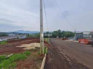 Vista de uma estrada de terra com vegetação e colinas ao fundo.