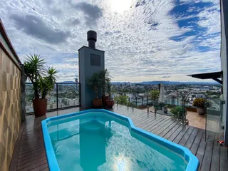 Foto de uma piscina externa com deck de madeira e vista panorâmica da cidade.