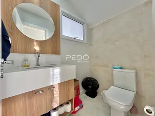 Foto de um banheiro com bancada branca e revestimento de parede claro.