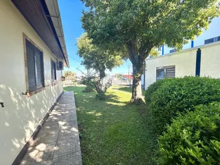 Foto da fachada de uma residência com jardim e vegetação.