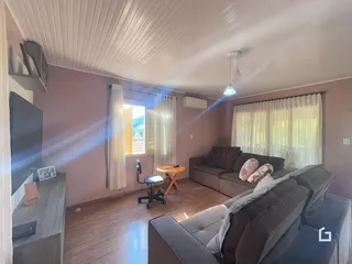 Sala de estar com piso de madeira e grandes janelas na residência.