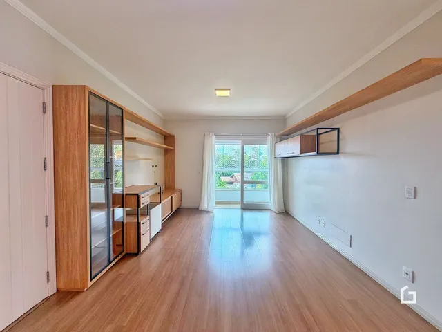 Uma sala de estar com piso de madeira clara e armários em madeira.
