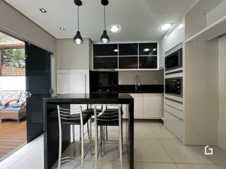 Imagem de uma cozinha moderna com bancada escura e armários brancos.