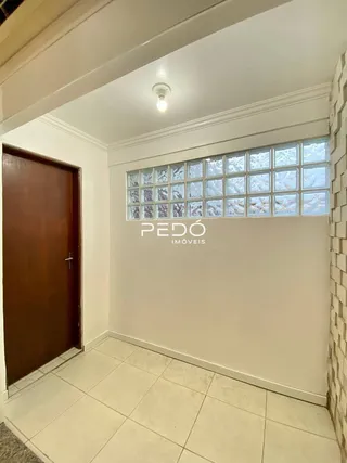 Interior de uma sala com parede branca e piso de cerâmica.