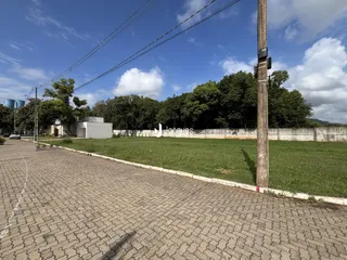 Vista externa de uma propriedade com cerca e vegetação ao lado de uma estrada.